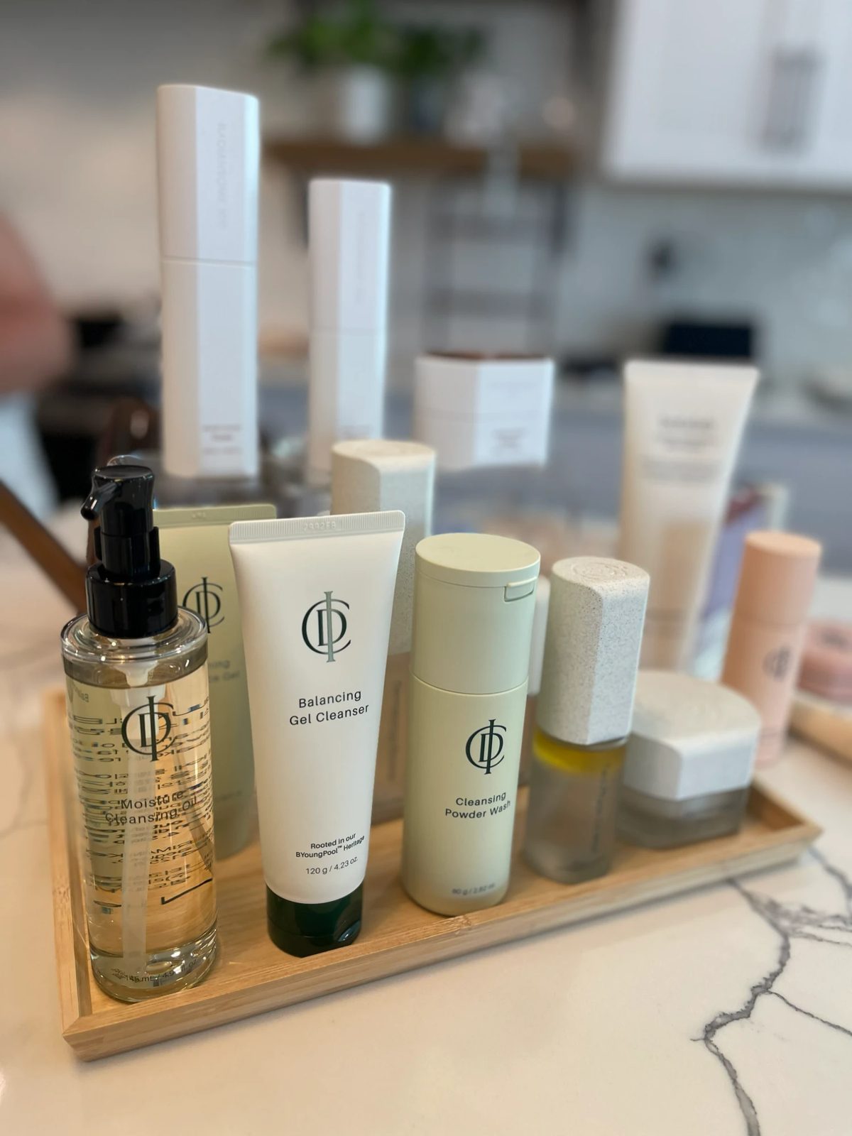 RIMAN cleansers lined up on a bamboo tray — Moisture Cleansing Oil, Balancing Gel Cleanser and Cleansing Powder Wash